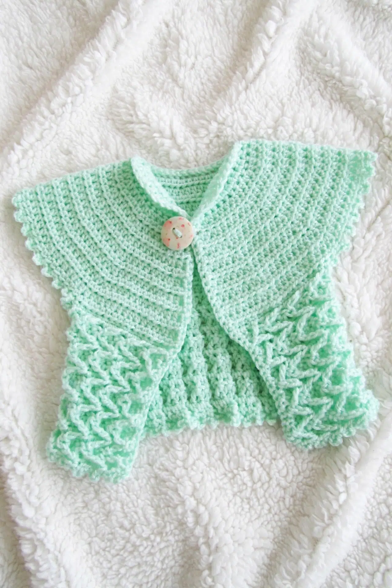 Summer Crochet Baby Cardigan shown at an angle with its textured crochet stitches.